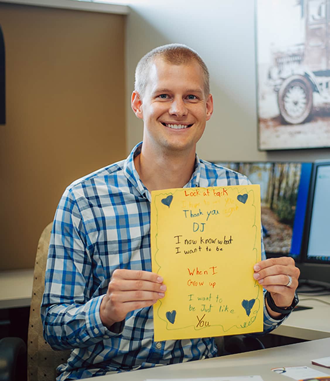 A man smiling and holding a piece of yellow paper