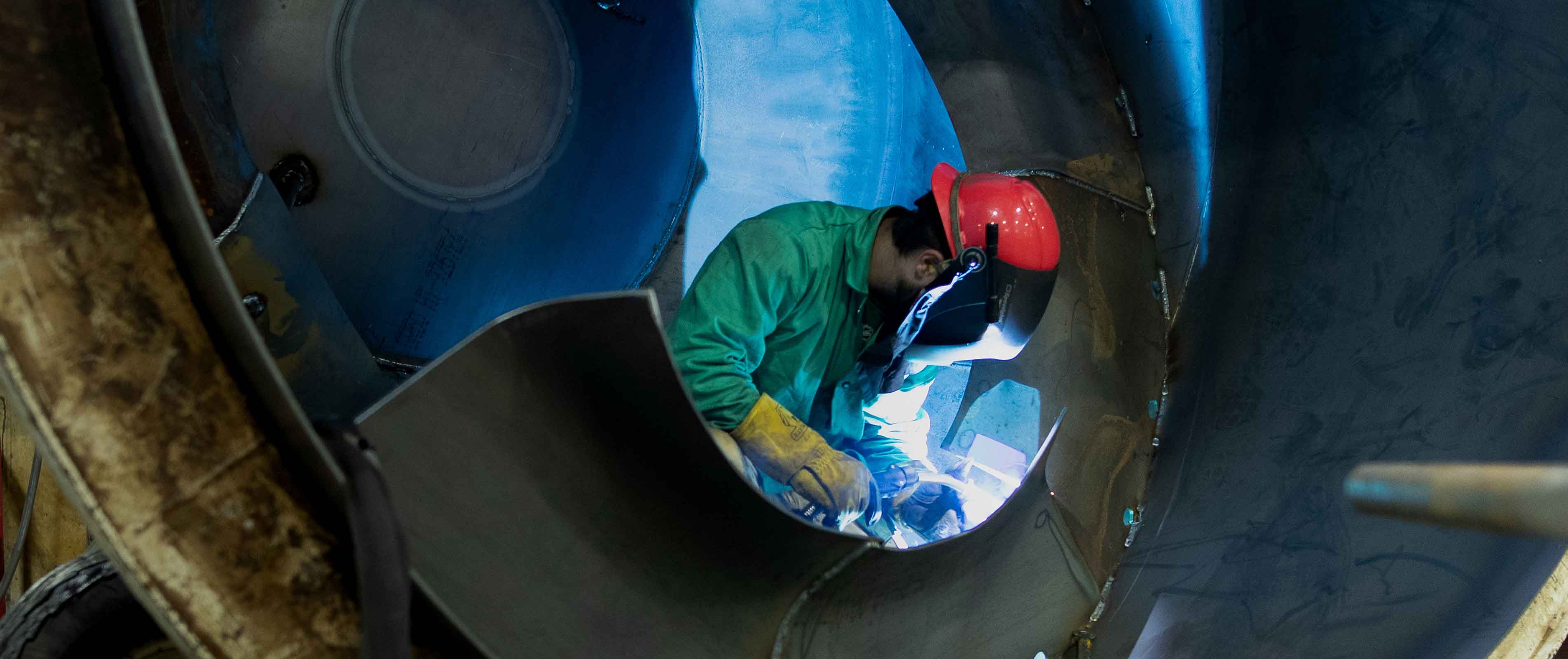 A man in a welding suit working inside of a vehicle.