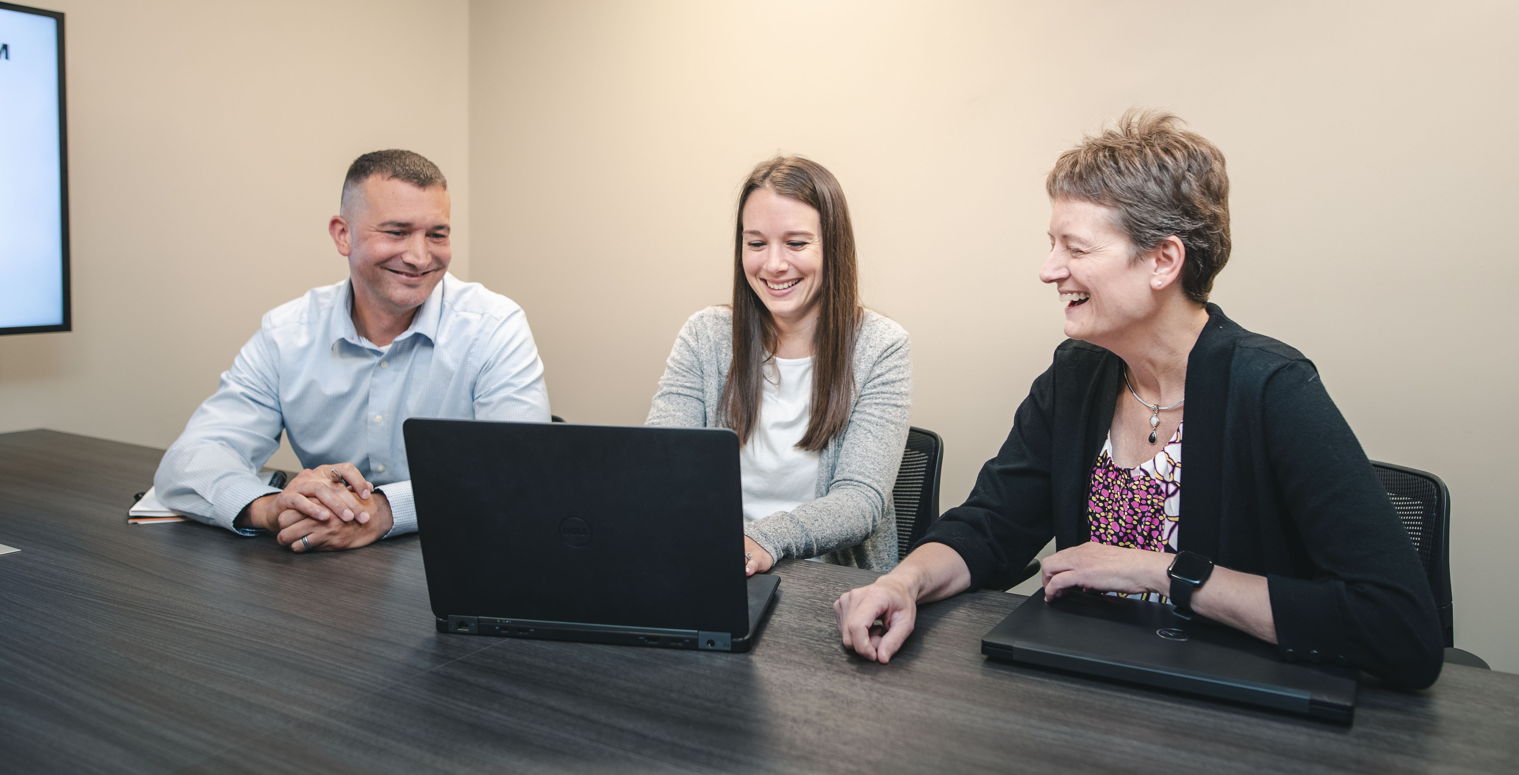 Man and two women sitting at a table working on a laptop