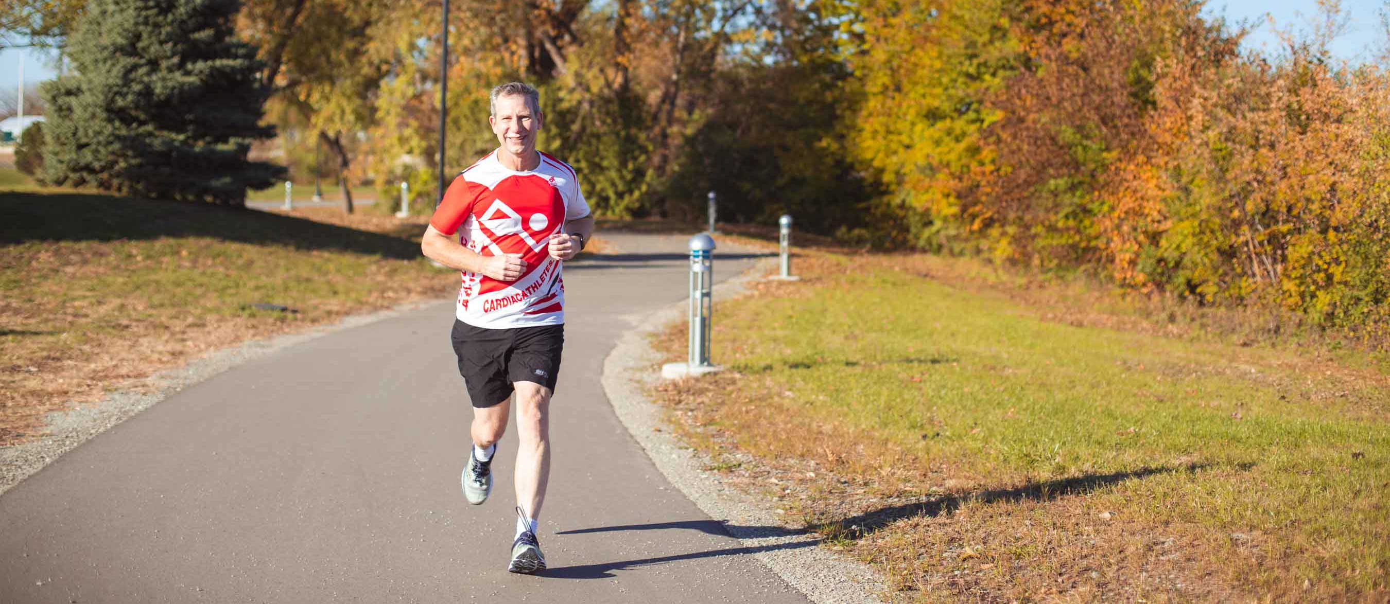 White man running outside on a paved trail in fall