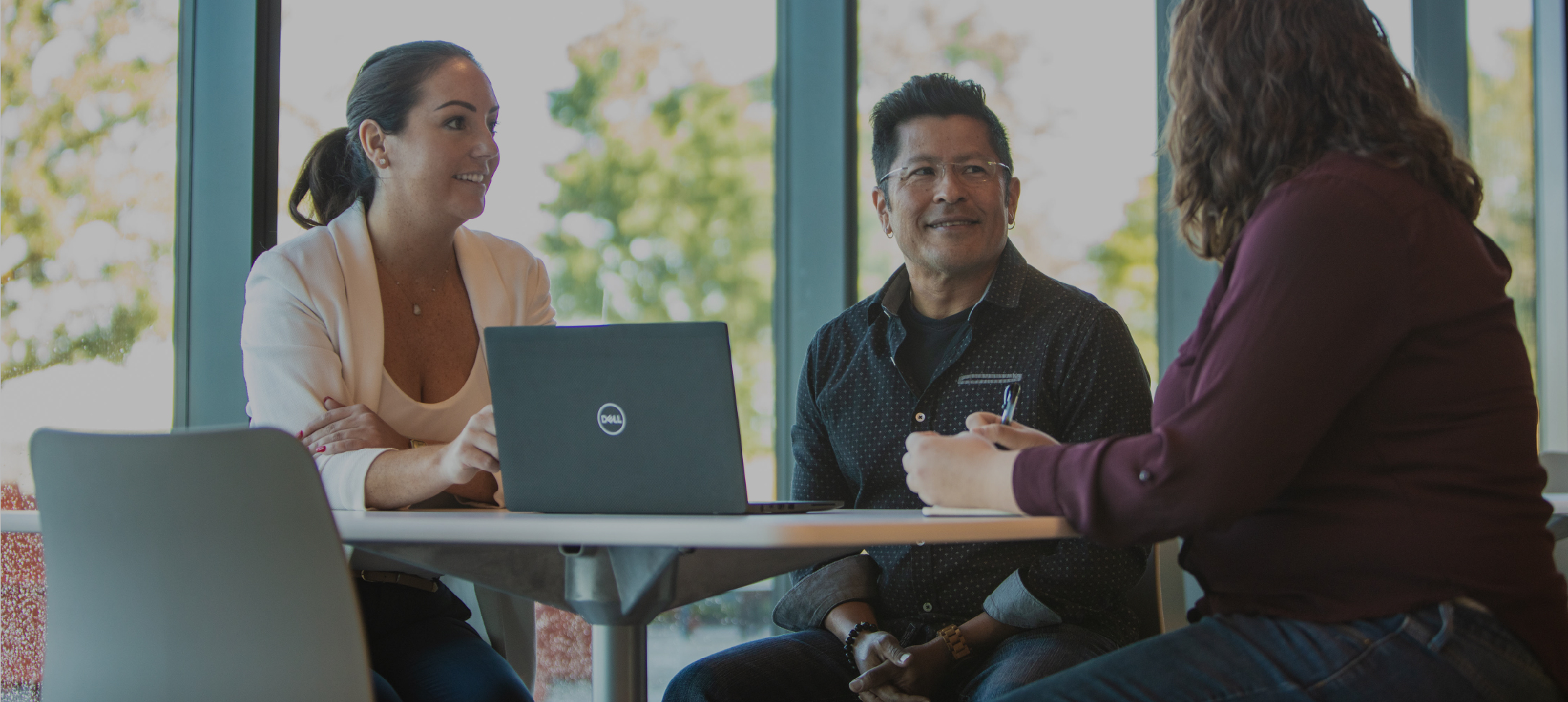 Two female and one male Oshkosh Corporation employee working together on a computer in an office facility