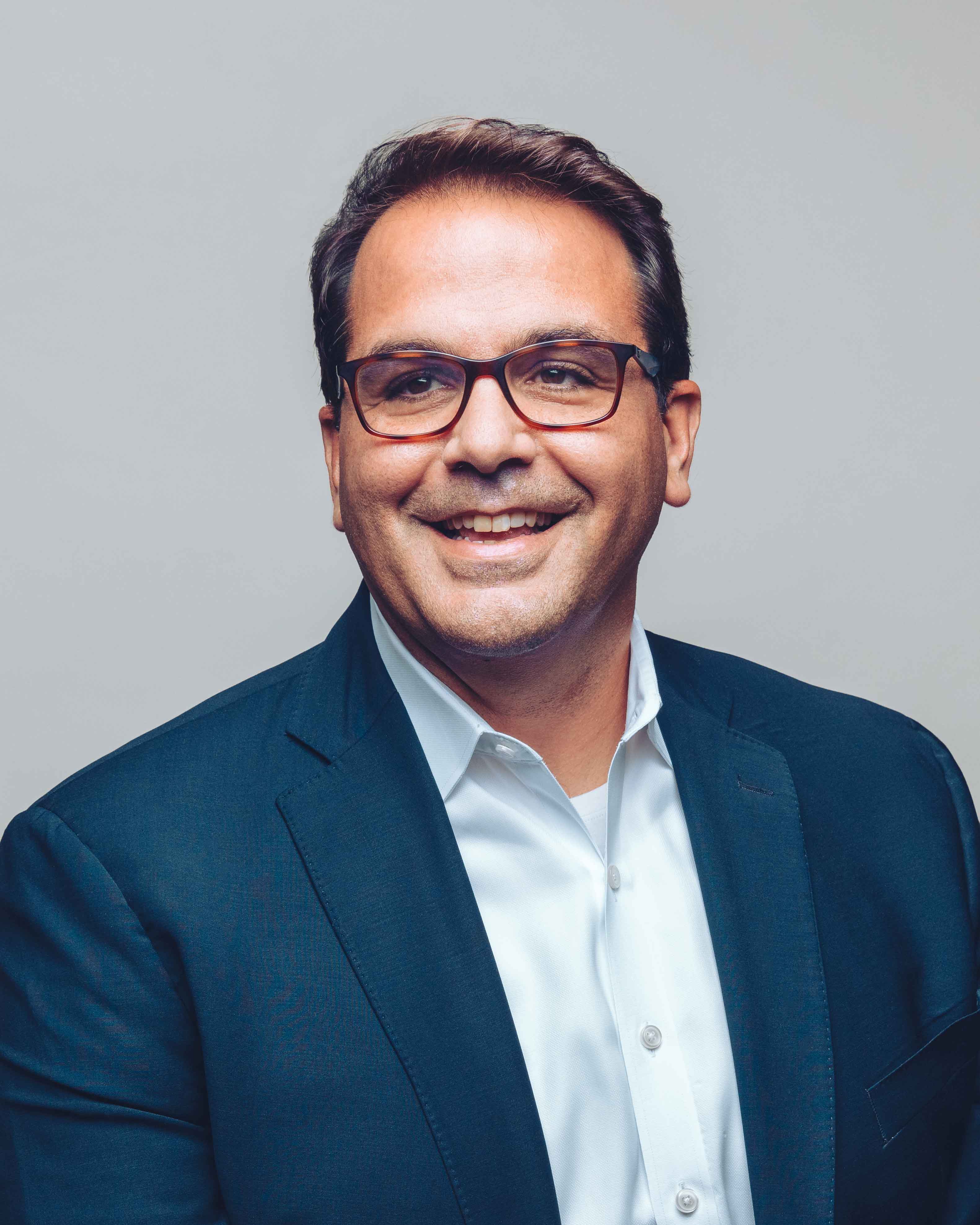 'Ignacio Cortina wearing a dark blue suit coat and smiling'